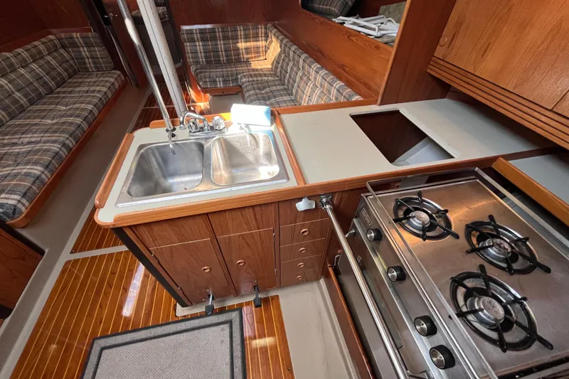 Slide: The Image of 1984 C&C 41 yacht interior with kitchen, stove, sink, and plaid seating. - 44