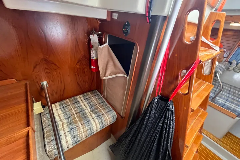 Slide: The Image of 1984 C&C 41 yacht interior with wooden finish, plaid seating, and fire extinguisher. - 51
