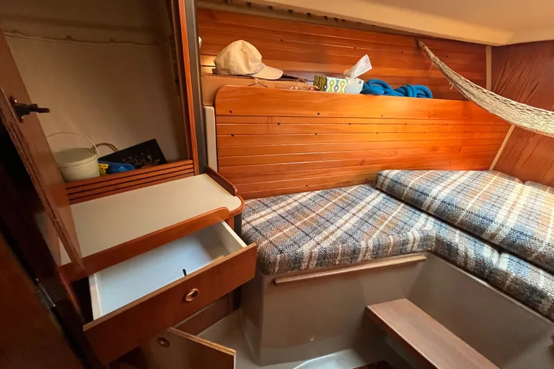 Slide: The Image of 1984 C&C 41 sailboat cabin with wooden interior, storage, and plaid bedding. - 52