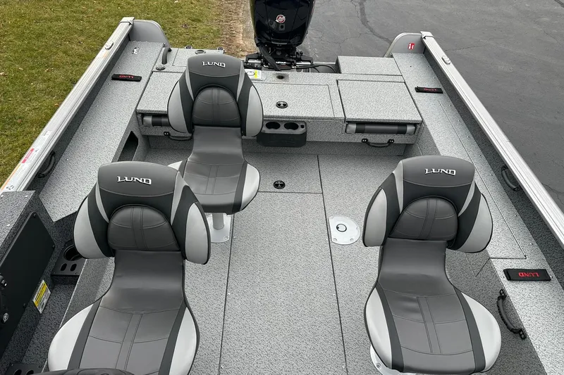 Slide: The Image of 2026 Lund 1875 Impact XS SS boat interior with four gray seats and storage compartments. - 12