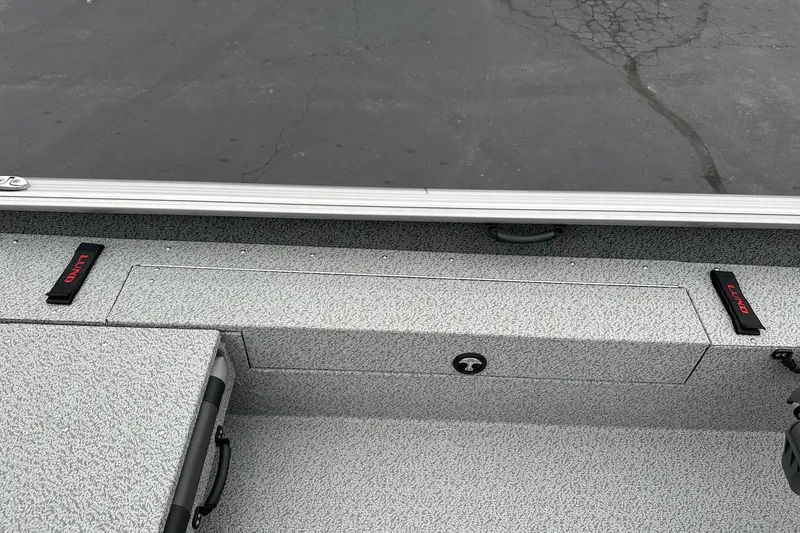 Slide: The Image of 2026 Lund 1875 Impact XS SS boat interior with storage compartments and textured flooring. - 19