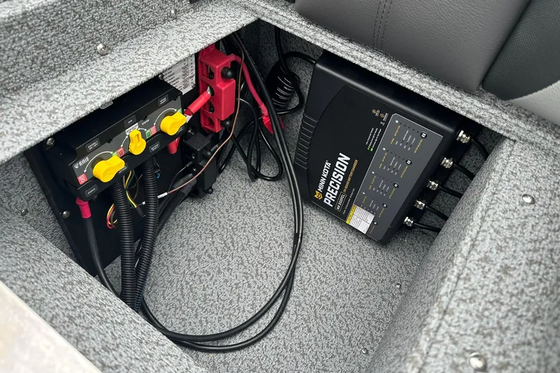 Slide: The Image of 2026 Lund 1875 Impact XS SS boat battery compartment with Minn Kota Precision charger. - 24