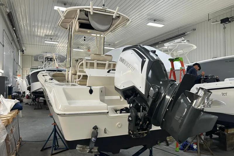 Slide: The Image of 2020 Sea Chaser 22 HFC boat in a workshop, featuring an Evinrude outboard motor. - 10