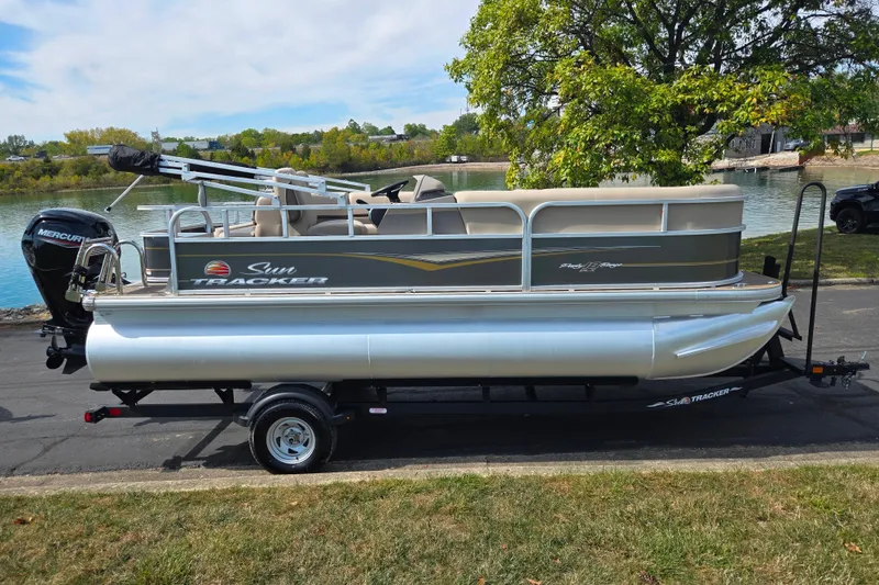 Slide: The Image of 2024 Sun Tracker Party Barge 18 DLX pontoon boat on trailer by a lake. - 10
