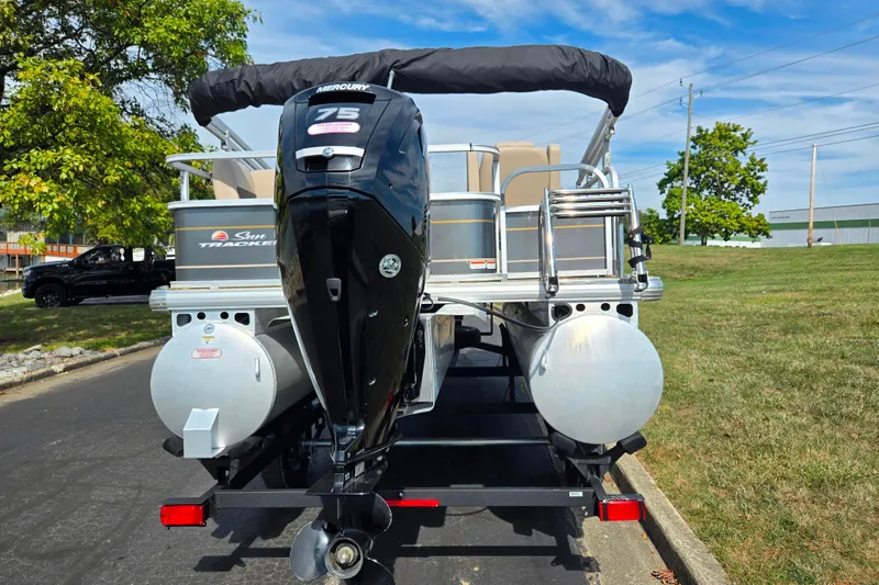 Slide: The Image of 2024 Sun Tracker Party Barge 18 DLX pontoon boat with Mercury 75 engine, parked outdoors. - 2