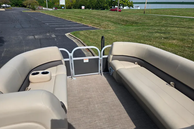 Slide: The Image of 2024 Sun Tracker Party Barge 18 DLX interior with beige seating and cup holders. - 20