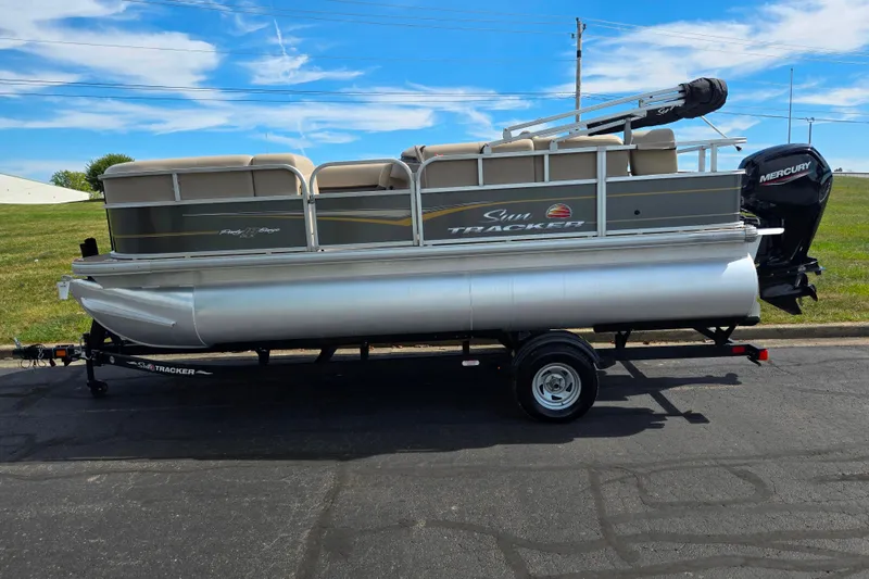 Slide: The Image of 2024 Sun Tracker Party Barge 18 DLX pontoon boat on trailer, parked outdoors. - 4