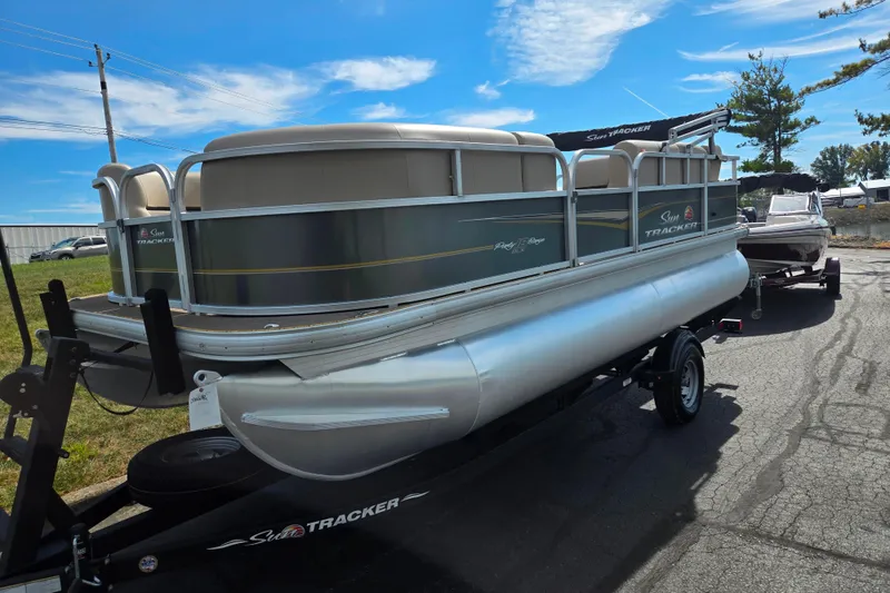 Slide: The Image of 2024 Sun Tracker Party Barge 18 DLX pontoon boat on trailer, parked outdoors. - 5
