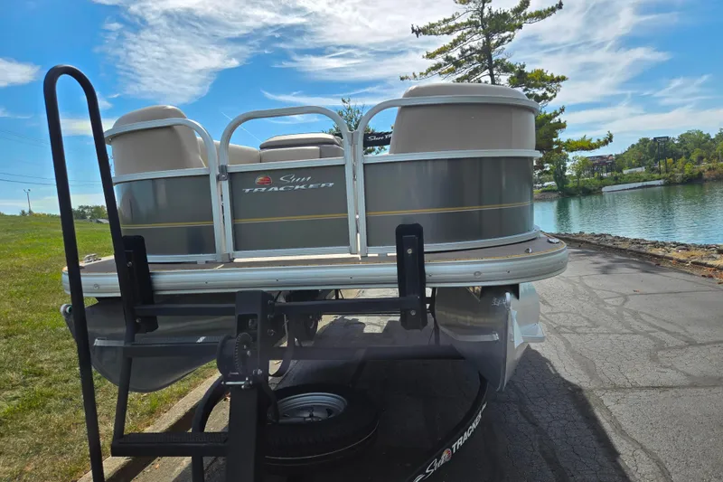 Slide: The Image of 2024 Sun Tracker Party Barge 18 DLX pontoon boat on trailer by a scenic lake. - 6