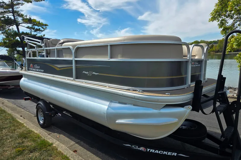 Slide: The Image of 2024 Sun Tracker Party Barge 18 DLX pontoon boat on trailer by a lake. - 9