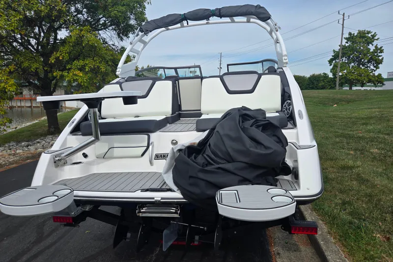 Slide: The Image of 2021 Yamaha Boats 252S rear view with seating and swim platform, parked outdoors. - 2