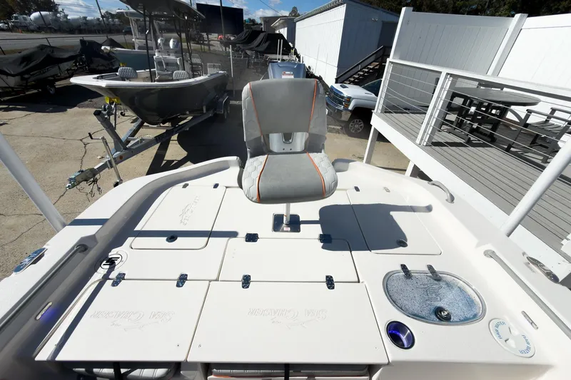 Slide: The Image of 2026 Sea Chaser 26 LX Special Edition boat interior with seating and console, parked outdoors. - 32