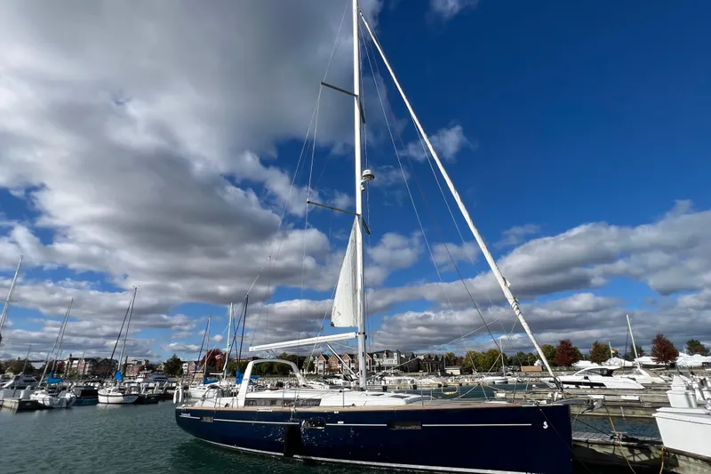 The Image of 2012 Beneteau Oceanis 45 sailboat docked in a marina under a cloudy sky. - 0
