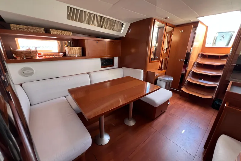 Slide: The Image of Interior of 2012 Beneteau Oceanis 45 yacht with wooden dining area and white seating. - 28