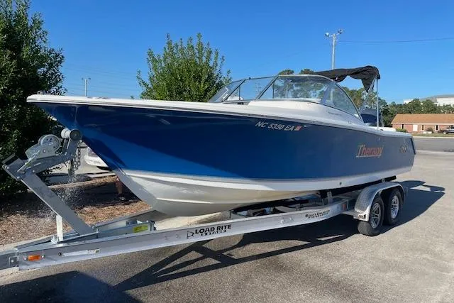 Slide: The Image of 2014 Sea Hunt Escape 235 SE boat on trailer, blue and white design, parked outdoors. - 1
