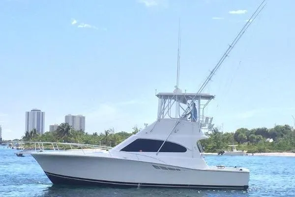 Slide: The Image of 2001 Luhrs 40 Convertible yacht on calm water with city skyline background. - 23