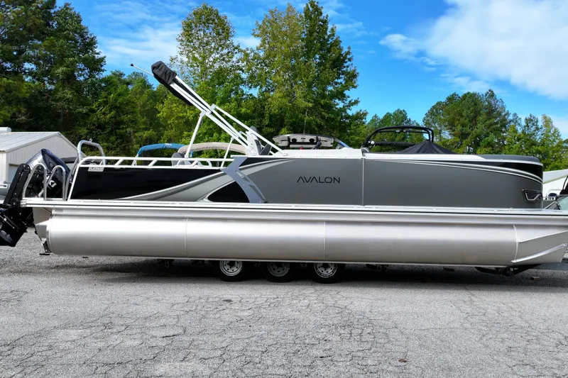 The Image of 2026 Avalon LSZ Entertainer pontoon boat on display, surrounded by trees and blue sky. - 0
