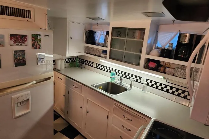 Slide: The Image of 1968 Burger Motor Yacht kitchen with white cabinets, checkered backsplash, and stainless steel sink. - 23
