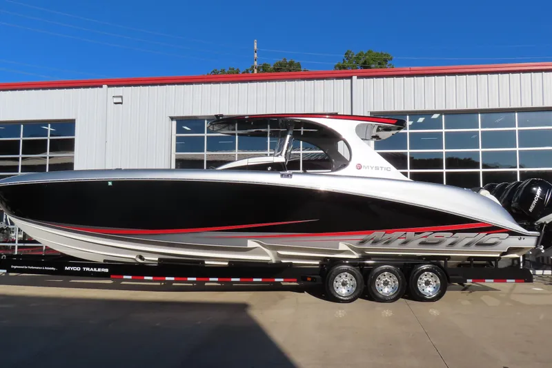 The Image of 2017 Mystic M4200 boat on trailer, sleek black and white design, parked outside a building. - 0
