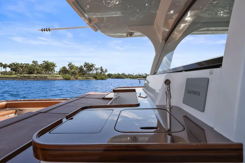 Slide: The Image of 2023 HCB 65 Estrella yacht deck with Garmin equipment, overlooking tropical waters and palm trees. - 13