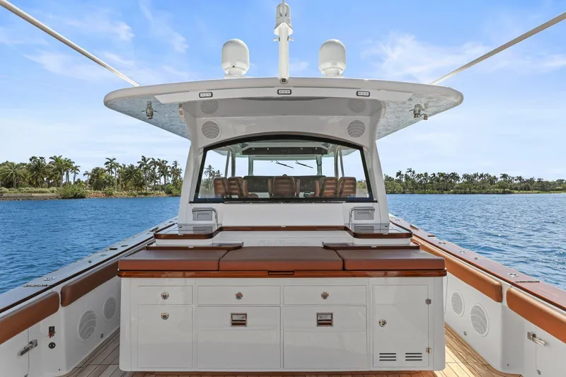 Slide: The Image of 2023 HCB 65 Estrella yacht interior with luxurious seating and cabinetry, set against a tropical backdrop. - 14