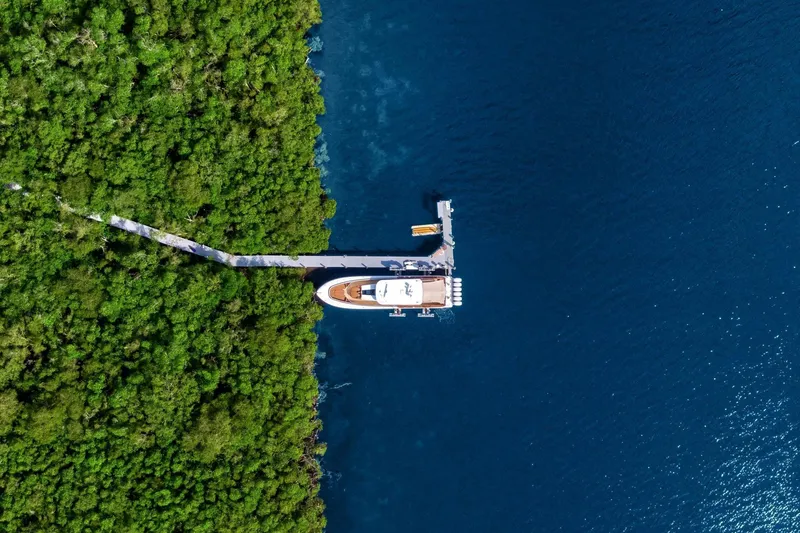 Slide: The Image of Aerial view of 2023 HCB 65 Estrella yacht docked by lush green forest. - 5