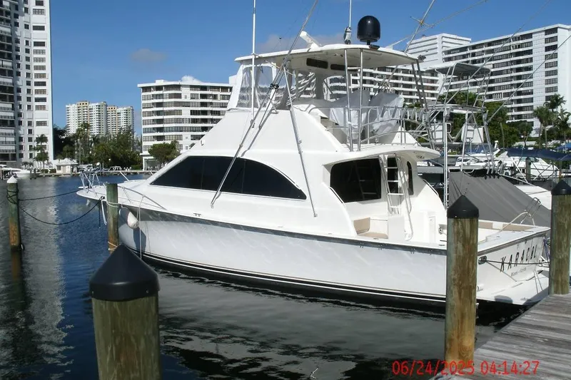 Slide: The Image of 1998 Ocean Yachts 48 Super Sport docked in a marina with modern buildings in the background. - 3