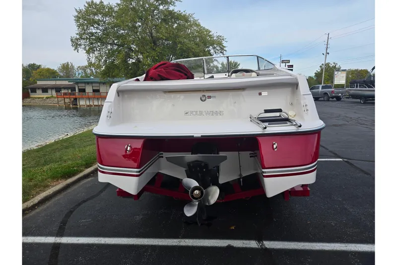 Slide: The Image of 1994 Four Winns 235 Sundowner boat, red and white, parked near a waterfront. - 2