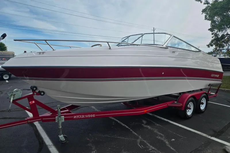 Slide: The Image of 1994 Four Winns 235 Sundowner boat on a red trailer in a parking lot. - 5