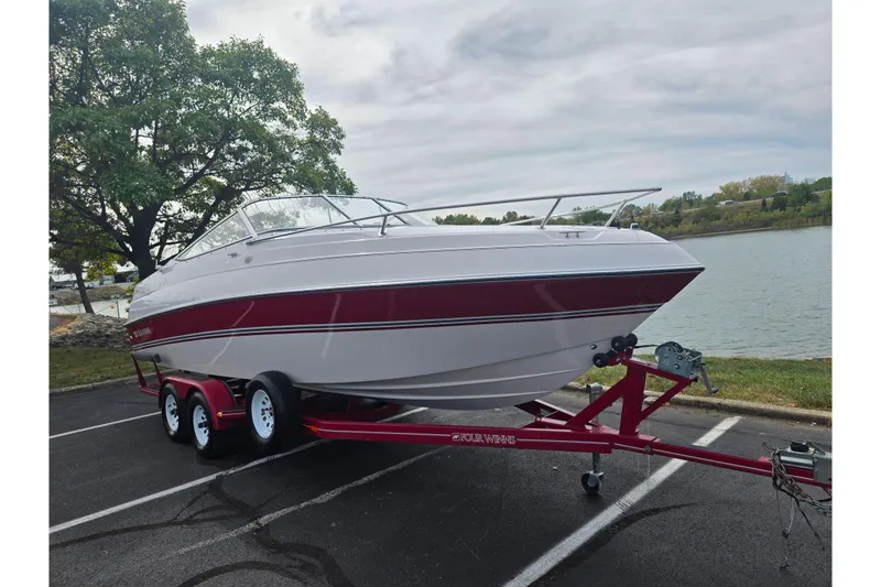 Slide: The Image of 1994 Four Winns 235 Sundowner boat on trailer by lakeside, featuring red and white design. - 8