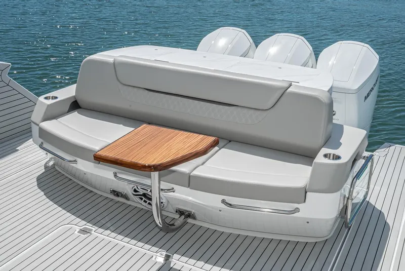 Slide: The Image of 2024 Cruisers Yachts 50 GLS rear seating area with wooden table and triple outboard engines. - 34