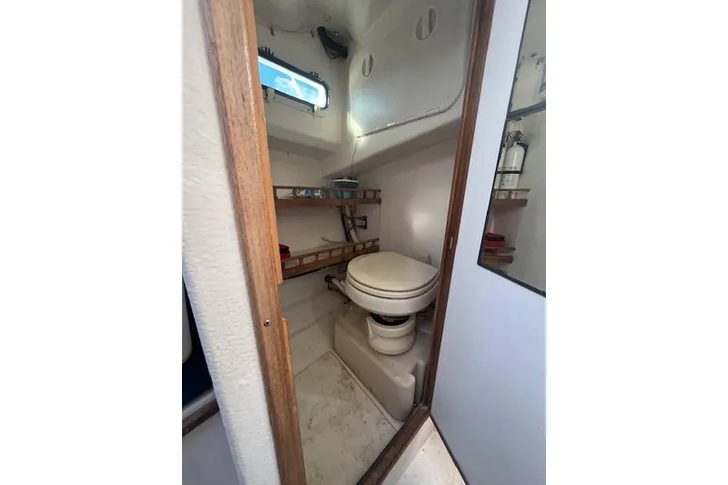Slide: The Image of 2007 Eastern 27 Islander boat bathroom with toilet, shelves, and window. - 11