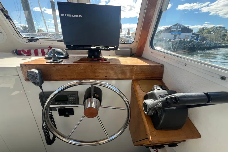 Slide: The Image of 2007 Eastern 27 Islander boat helm with steering wheel, navigation equipment, and scenic view. - 6