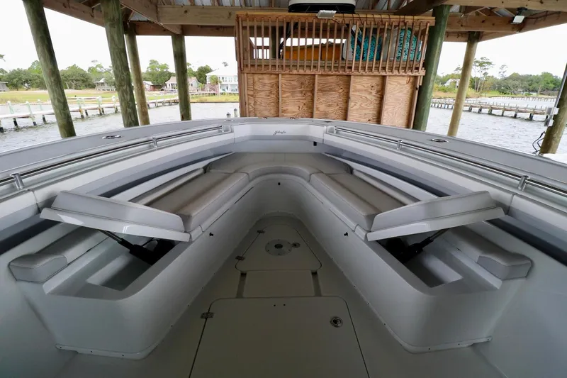 Slide: The Image of 2023 Yellowfin 42 Offshore boat interior with cushioned seating under a wooden dock. - 11