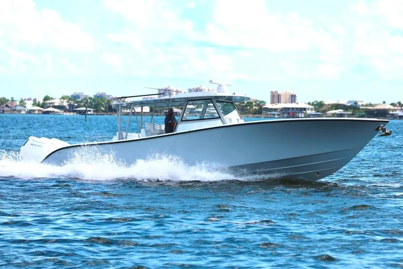 Slide: The Image of 2023 Yellowfin 42 Offshore boat cruising on blue water, cityscape in background. - 33