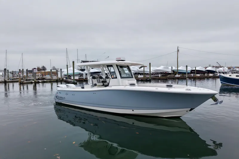 The Image of 2025 Robalo R300 Center Console boat docked in a marina, overcast sky. - 0