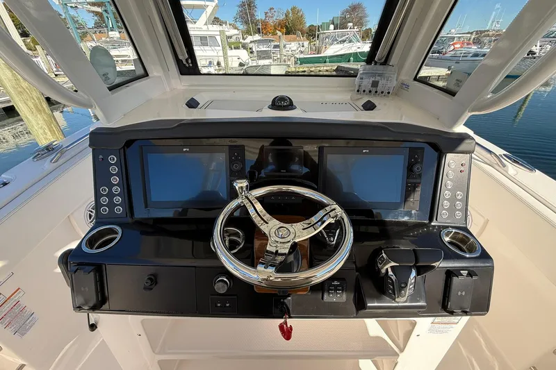 Slide: The Image of 2025 Robalo R300 Center Console boat with dual engines at a marina dock. - 12