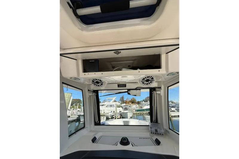 Slide: The Image of 2025 Robalo R300 Center Console boat at marina, showcasing open storage compartment. - 14