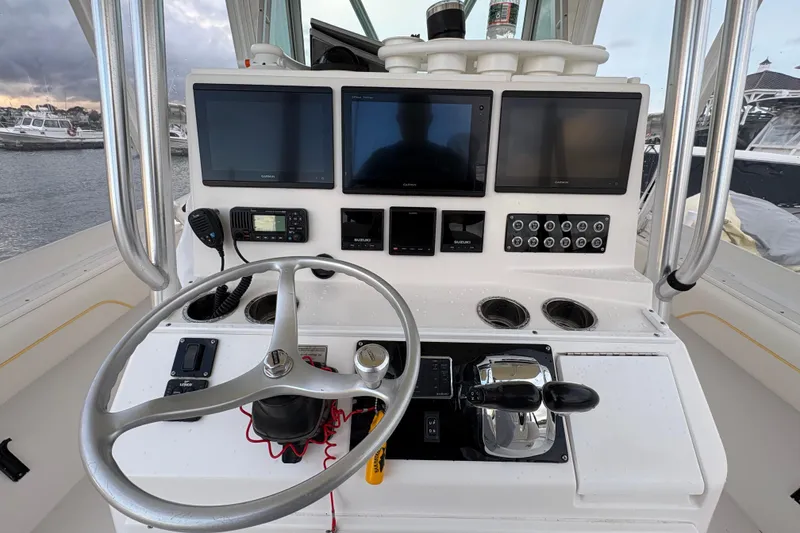 Slide: The Image of Control panel of a 2006 Regulator 32 Forward Seating boat with steering wheel and navigation screens. - 14