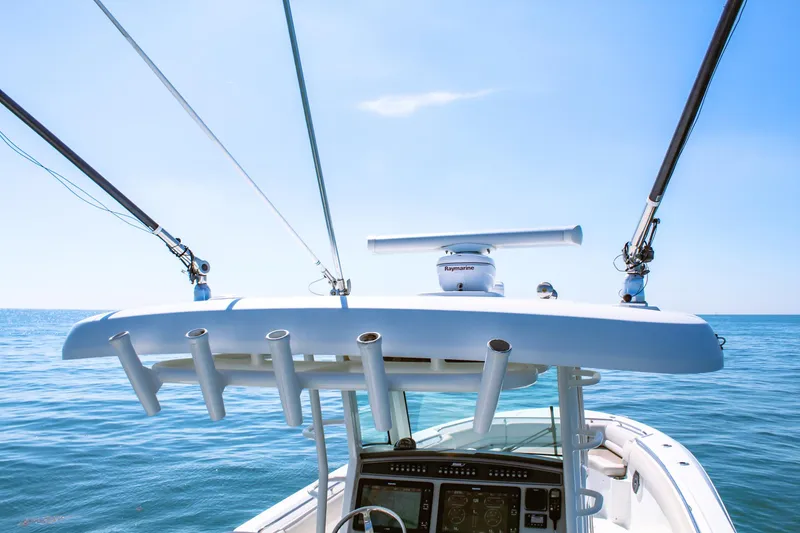 Slide: The Image of 2017 Boston Whaler 330 Outrage boat with fishing rod holders, ocean view, and clear blue sky. - 6