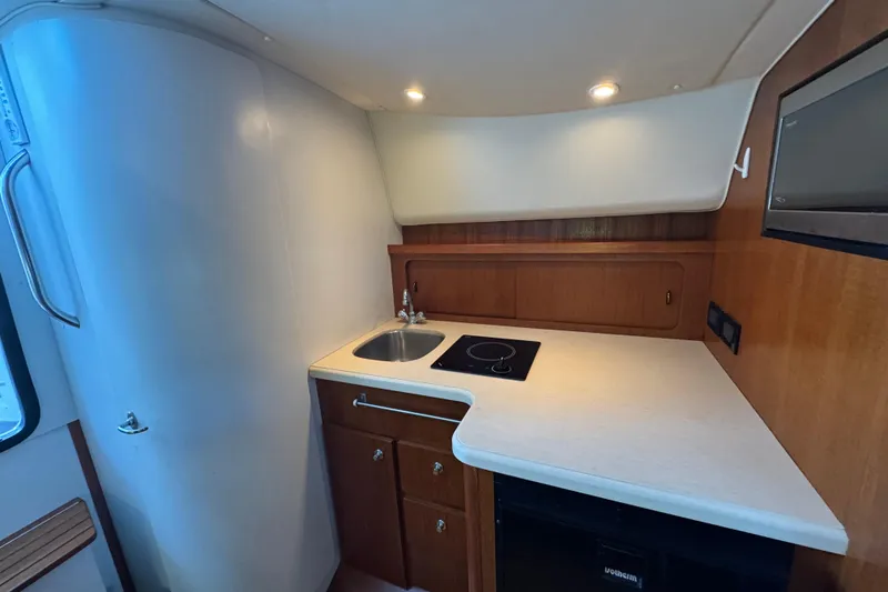 Slide: The Image of 2005 Tiara Yachts 2900 Open galley with sink, stovetop, and wooden cabinetry. - 13