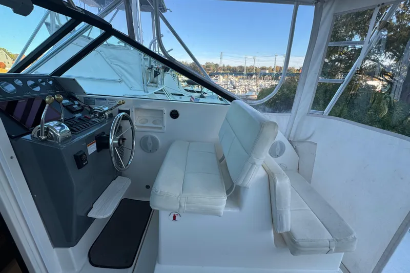 Slide: The Image of 2005 Tiara Yachts 2900 Open helm with white seating and marina view. - 9