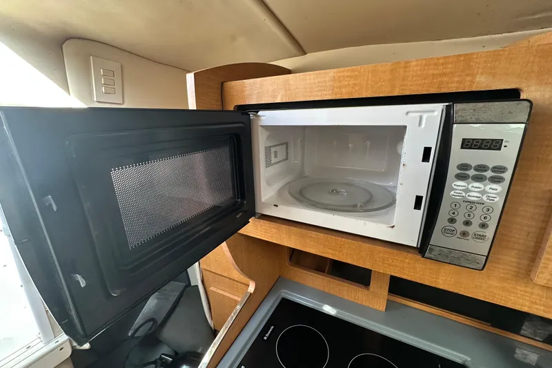 Slide: The Image of Open microwave in 2014 Larson Cabrio 265 boat kitchen, showcasing modern appliances. - 28