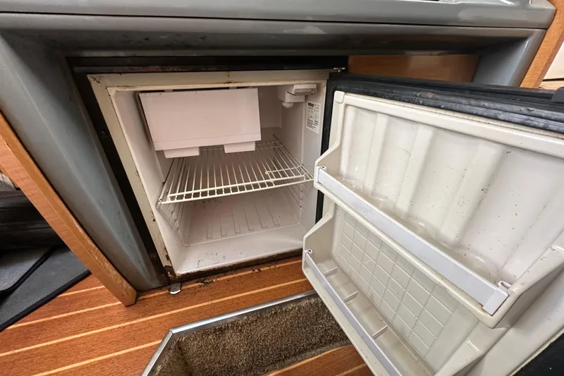Slide: The Image of Open mini fridge inside 2014 Larson Cabrio 265 boat, showing empty shelves. - 32