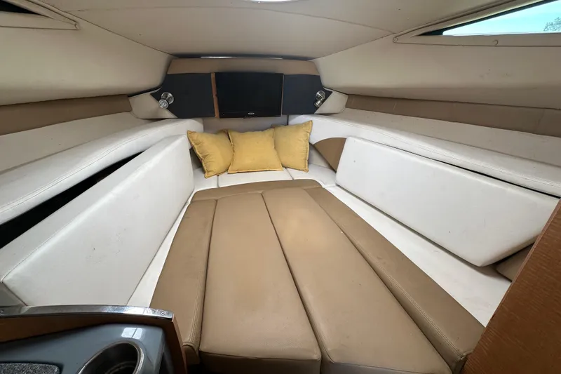 Slide: The Image of 2014 Larson Cabrio 265 cabin interior with beige seating and yellow cushions. - 34
