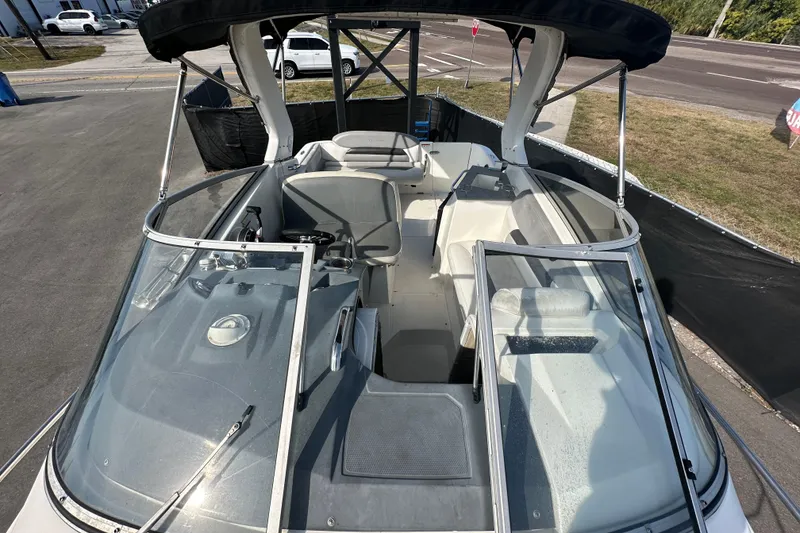 Slide: The Image of 2014 Larson Cabrio 265 boat interior with seating and windshield, parked on pavement. - 54