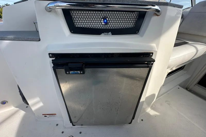 Slide: The Image of 2014 Larson Cabrio 265 boat interior with built-in mini fridge. - 60
