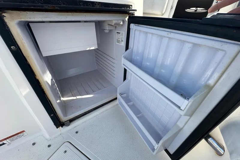 Slide: The Image of Open refrigerator on 2014 Larson Cabrio 265 boat, showing interior shelves and compartments. - 61