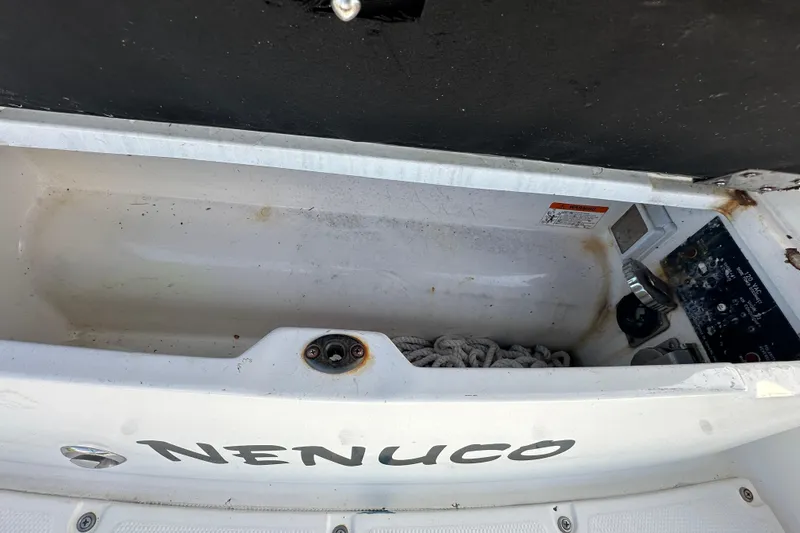 Slide: The Image of Open storage compartment on 2014 Larson Cabrio 265 boat with rope and control panel. - 77