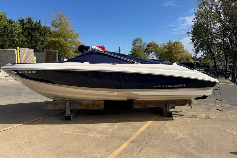 The Image of 2007 Regal 2000 Bowrider boat on trailer, parked outdoors under clear sky. - 0